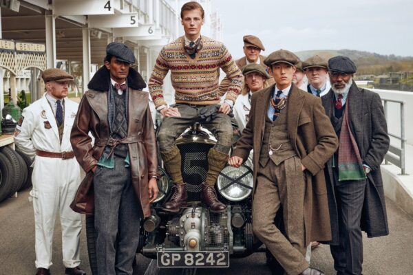 Nine male models posing around a pre-War car