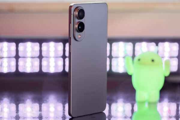Samsung Galaxy S25 Edge from a 3/4 angle with black lights and an Android figuring blurred in the background