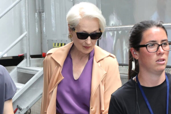 Meryl Streep in character as Miranda Priestly wearing a purple top and carrying a Collina Strada water bottle