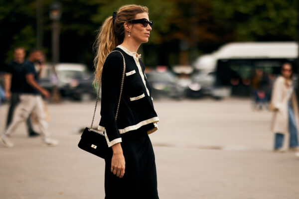 An attendee at Paris Fall Winter 2025, Haute Couture fashion week with a white and black sweater, sunglasses, and black crossbody bag