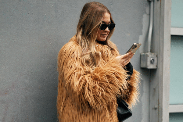 woman wearing a fur coat in New york with sunglasses and a phone.