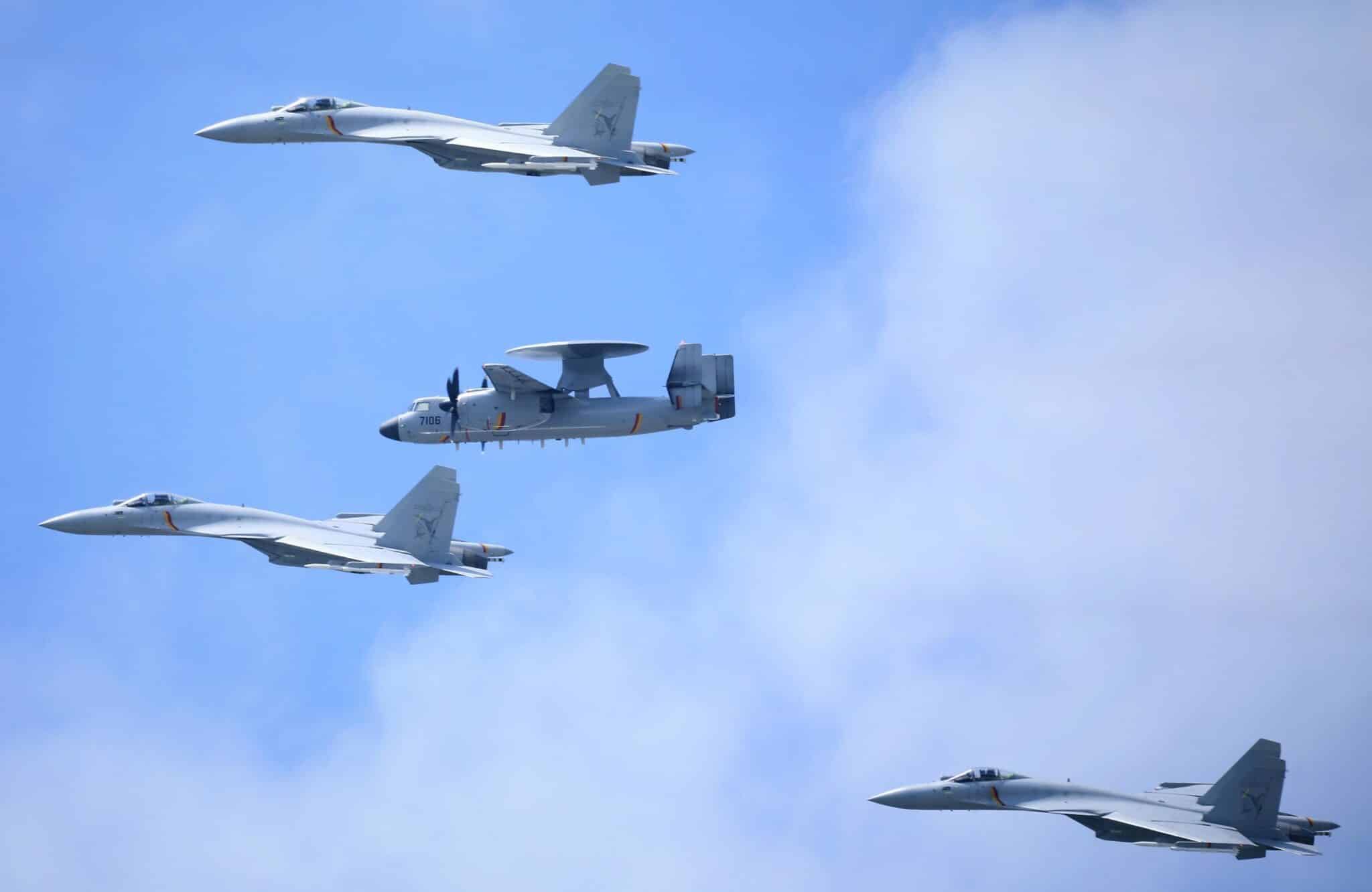 Jetfighters and radar surveillance aircraft flying in front of cloudy sky.
