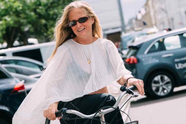 Female on bicycle wearing white sheer pleated shirt and sunglasses at Copenhagen Spring 2026 Fashion Week