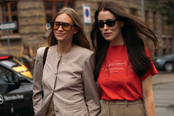 woman wearing a tan blazer and jeans next to a woma in a red tee and a brown skirt
