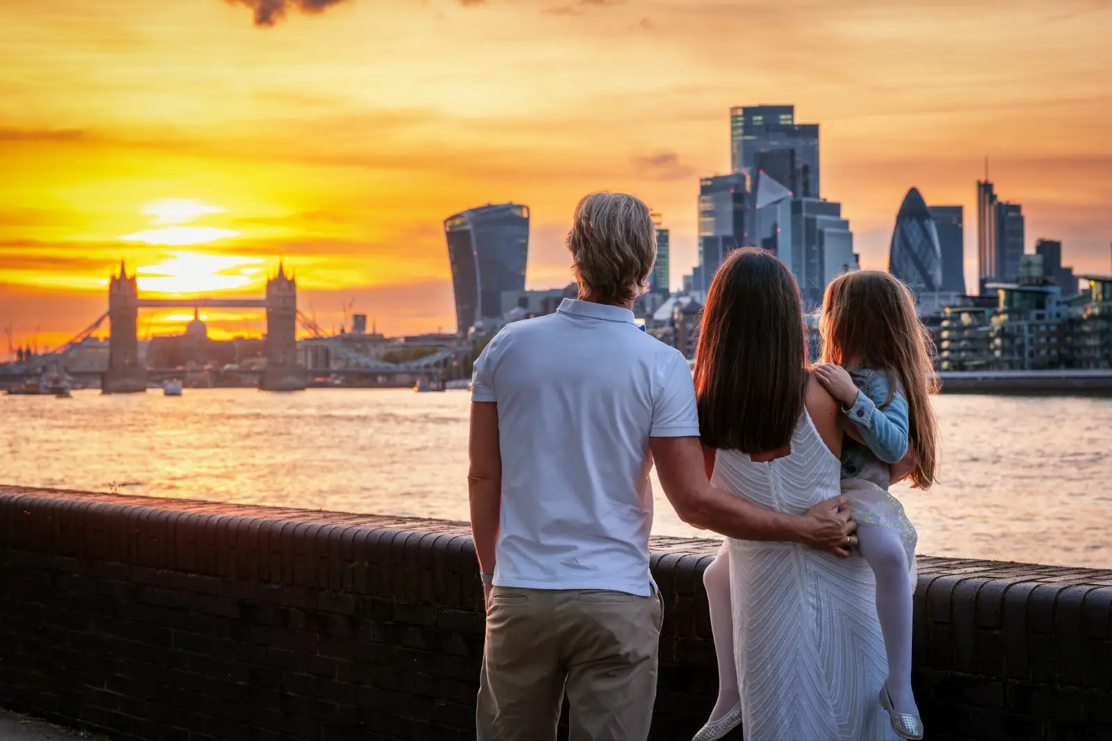Family watching a sunset over the River Thames with Tower Bridge and London skyline in the background.