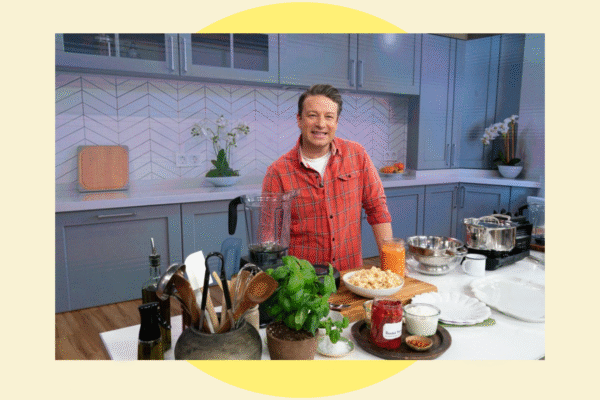 Jamie Oliver standing in a kitchen with various ingredients