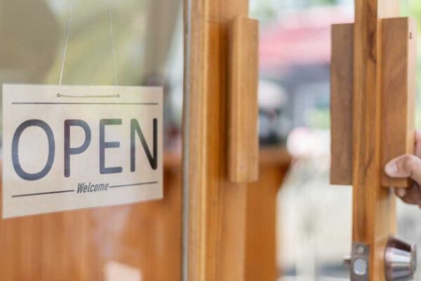 A photograph of a door with a sign reading "OPEN Welcome" hanging in the window.