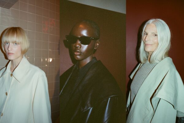 three models with dewy skin wearing black and white jackets against a red wall