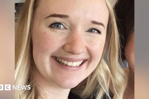 A close-up photo of Jessica Brady who is smiling broadly and looking directly at the camera, with long blonde hair, brown eyes and a visible earing in her left ear.