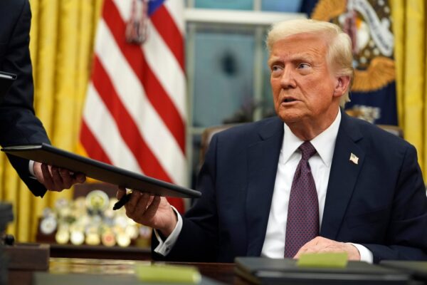 President Donald Trump signs executive orders in the Oval Office of the White House on Jan. 20.