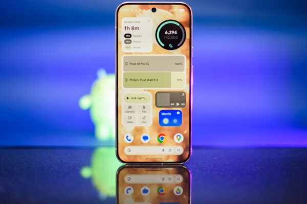 Google Pixel 10 Pro XL in Porcelain against a blue background with a green neon Android figurine in the background