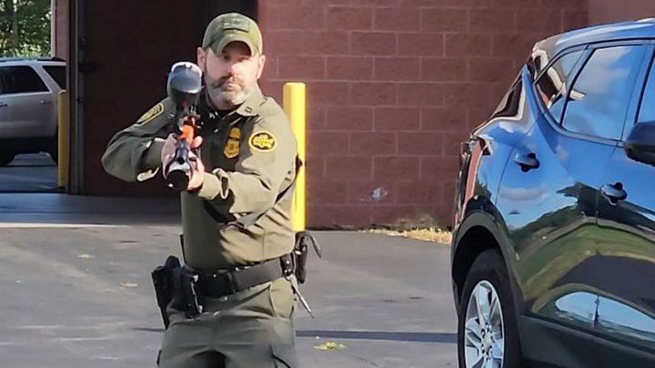 A border patrol agent holds a 'less-lethal-control-device'.