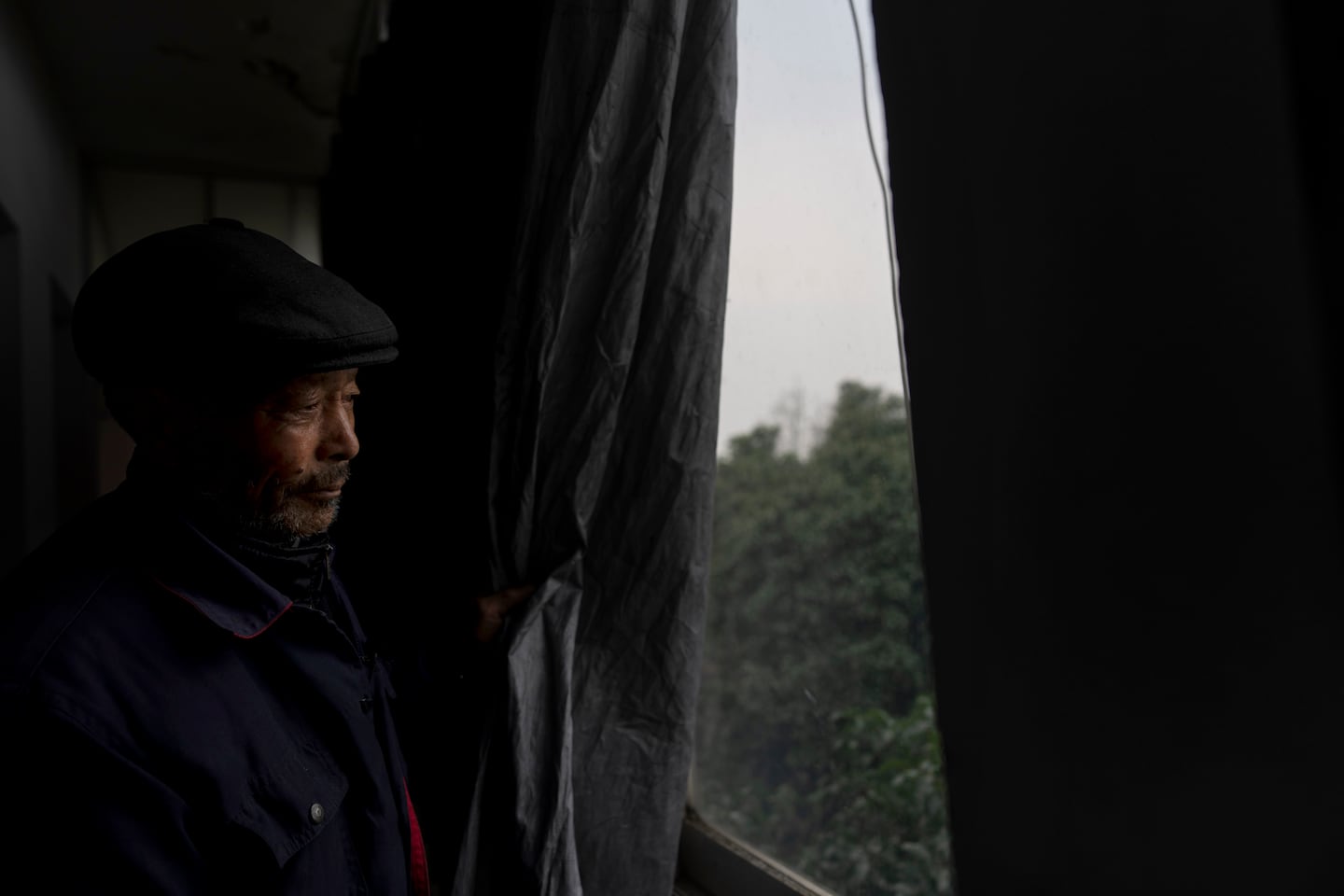 Petitioner Yang Guoliang pulls back the blackout curtain used to provide privacy from nearby police security cameras and lights during an interview at his home in Changzhou in eastern China's Jiangsu Province, on Dec. 13.