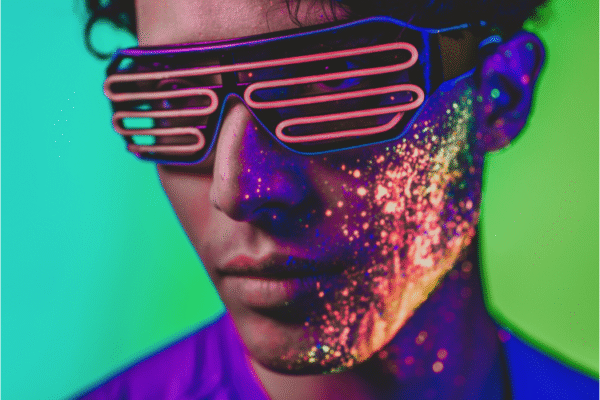 Young man with glow paint on face wearing led light glasses