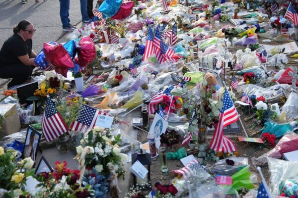 A well-wisher pauses at a growing makeshift memorial set up at the Turning Point USA headquarters after the shooting death at a Utah college last Wednesday of Charlie Kirk, the 31-year-old founder and CEO of the organization, Wednesday, Sept. 17, 2025, in Phoenix. (AP Photo/Ross D. Franklin)