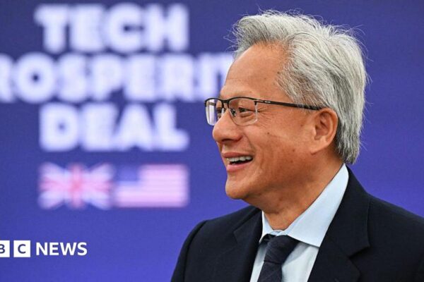 Nvidia CEO Jensen Huang at a Business event hosted by US President Donald Trump and Britain's Prime Minister Keir Starmer. He is smiling and wearing a suit with a tie. He has grey hair and wears glasses.