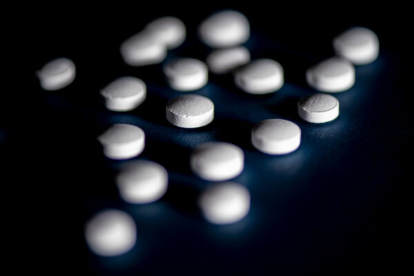 Small white medication tablets shown against a black backdrop.