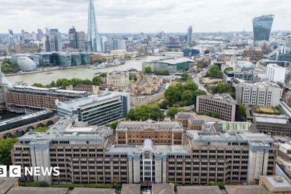 Aerial view of the old Royal Mint Court in London on a cloudy day with the River Thames, Tower of London and the Shard in the background