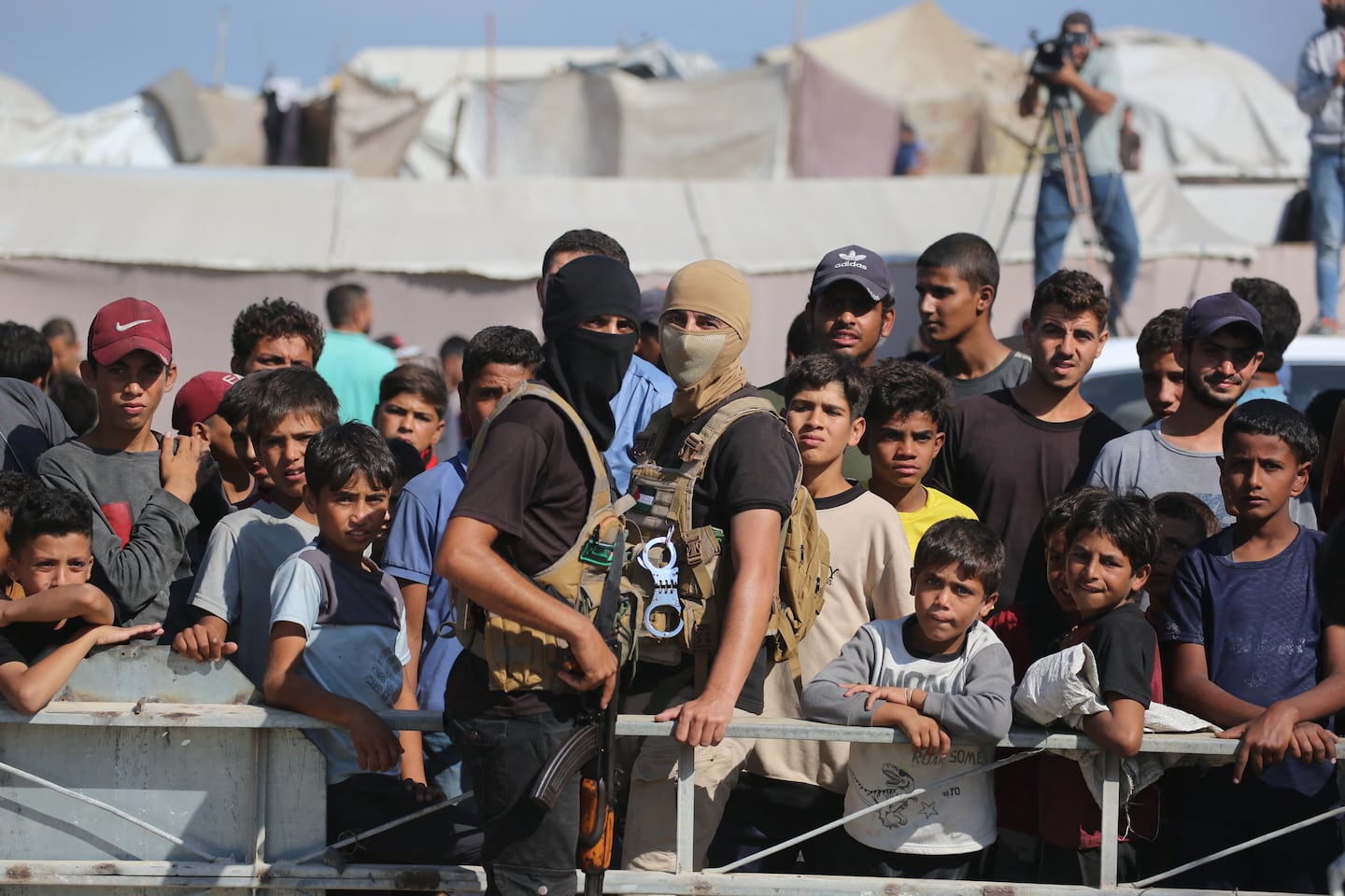 Palestinian militants of the Ezzedine al-Qassam Brigades, the military wing of Hamas, stood guard next to a crowd watching the transfer of released Israeli hostages to the Red Cross in the central Gaza Strip, on Oct. 13.