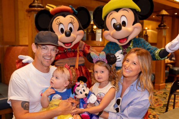 Charli D’Amelio, Ashley Tisdale, Anthony Gonzalez, and More Celebrities Visit Disney Parks A happy family with two children poses with Mickey and Minnie Mouse at a Disney park restaurant, not far from Cinderella Castle.