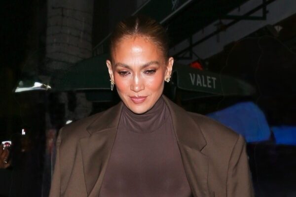 Jennifer Lopez wears a brown dress and matching jacket, carries a furry clutch, and wears peep-toe platforms