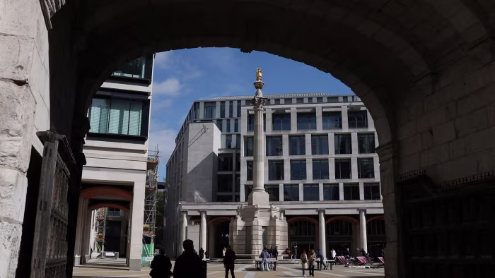 People walk near the London Stock Exchange in Paternoster Square, London