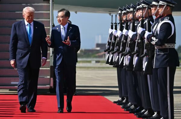 Donald Trump is greeted by South Korea’s foreign minister Cho Hyun at the base of airplane stairs, with guards and an honour guard present