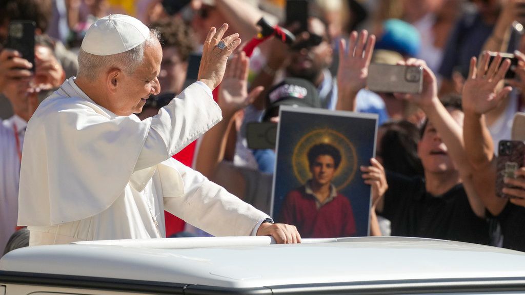 Pope Leo XIV waves to faithful holding a picture of Blessed Carlo Acutis, who will be canonized Sunday, as he arrives in St. Peter's Square at the Vatican for an open-air jubiliar audience Saturday, Sept. 6, 2025. (AP Photo/Andrew Medichini)