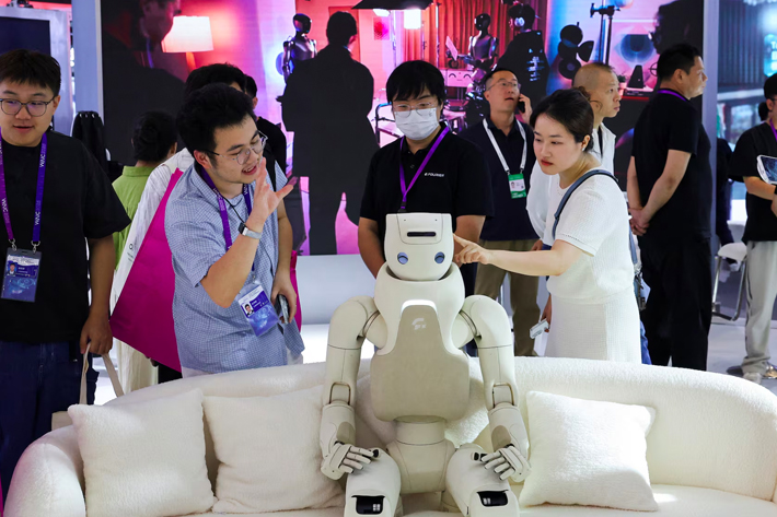 People interact with a humanoid robot at a Fourier booth during the World Artificial Intelligence Conference in Shanghai, China.