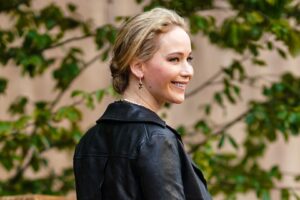 Jennifer Lawrence on a red carpet wearing a leather jacket and jeans