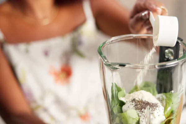 Young woman making a smoothie with protein powder