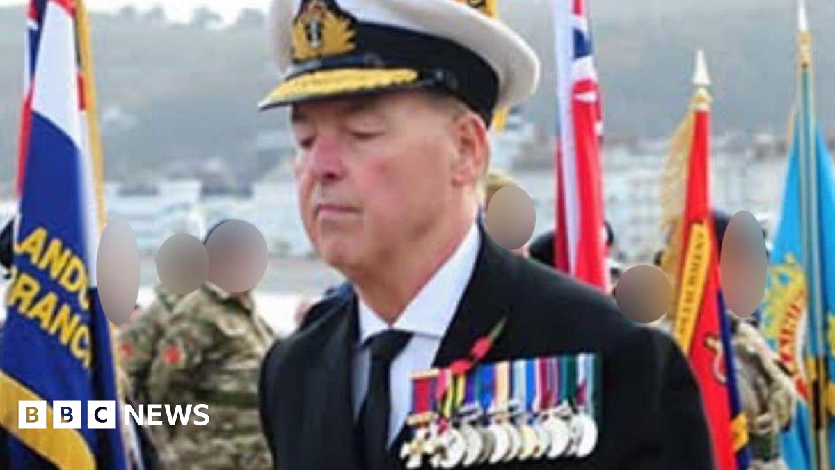 Close-up of the array of medals the man was wearing. He wears a black jacket, black tie and white shirt. A Remembrance Day poppy is pinned above the medals.