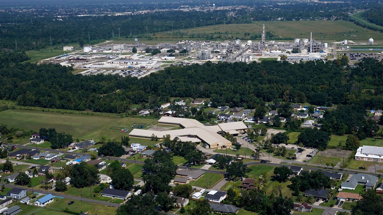 The Fifth Ward Elementary School and residential neighborhoods sit near the Denka Performance Elastomer Plant, back, in Reserve, La., Sept. 23, 2022. (AP Photo/Gerald Herbert)