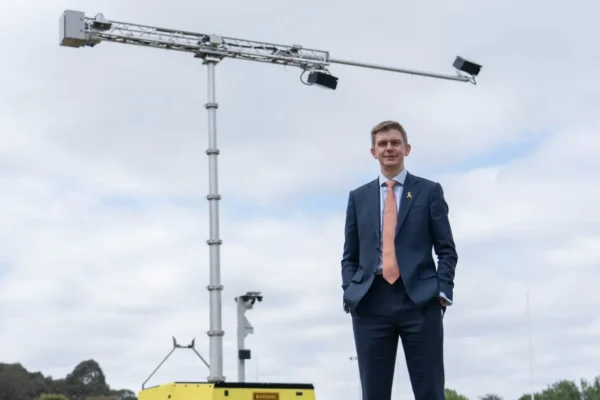 Acusensus managing director Alexander Jannink standing with a gantry mounted camera behind him against a cloudy sky