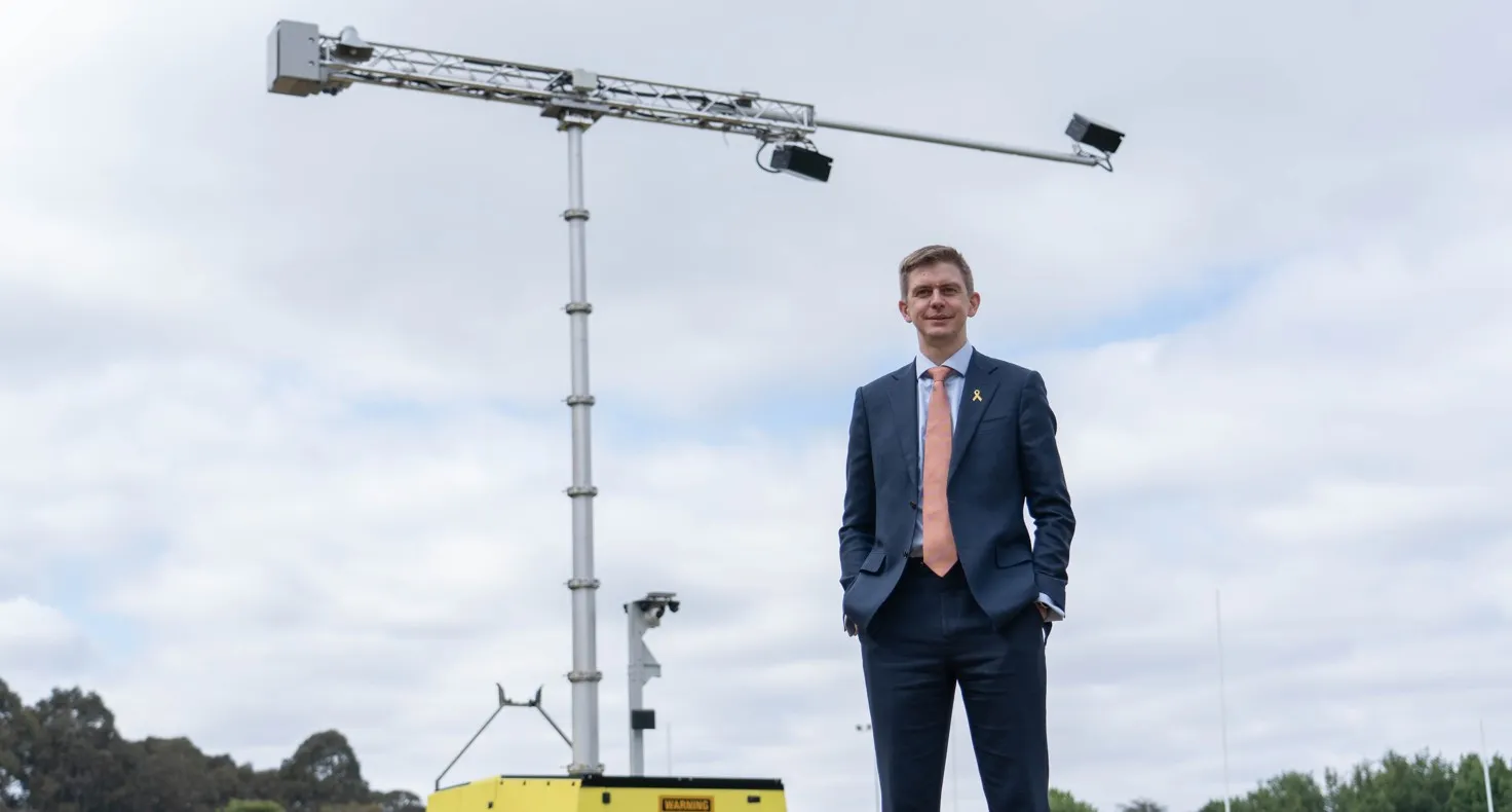 Acusensus managing director Alexander Jannink standing with a gantry mounted camera behind him against a cloudy sky