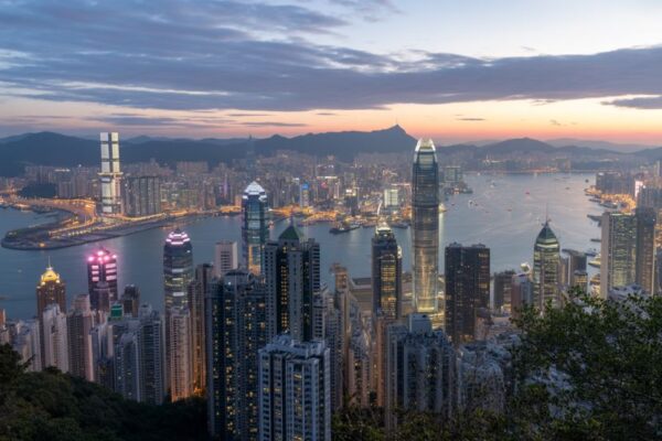 Stunning view of hong kong skyline at dusk, showcasing towering skyscrapers, victoria harbour, and the lush mountains in the background. The vibrant city lights illuminate the waterfront, offering a breathtaking panoramic perspective of the city's dynamic urban landscape. Perfect for a travel-focused image highlighting hong kong’s modernity and natural beauty