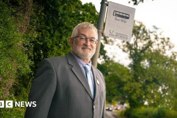 A man in a suit stands by a bus stop