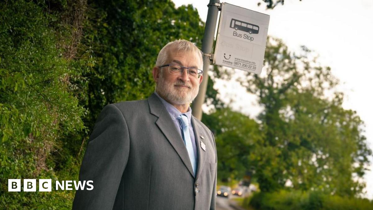A man in a suit stands by a bus stop