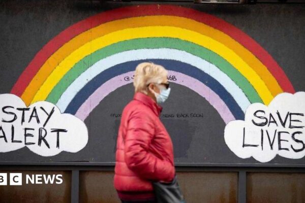 Woman walking down street past Covid sign