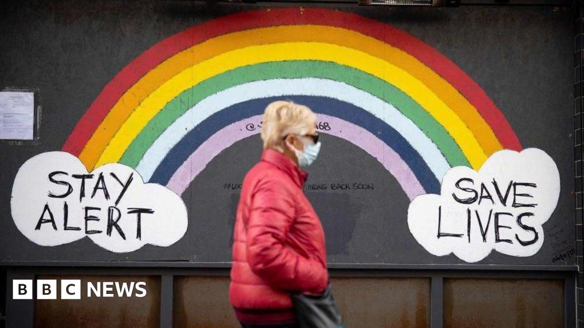 Woman walking down street past Covid sign