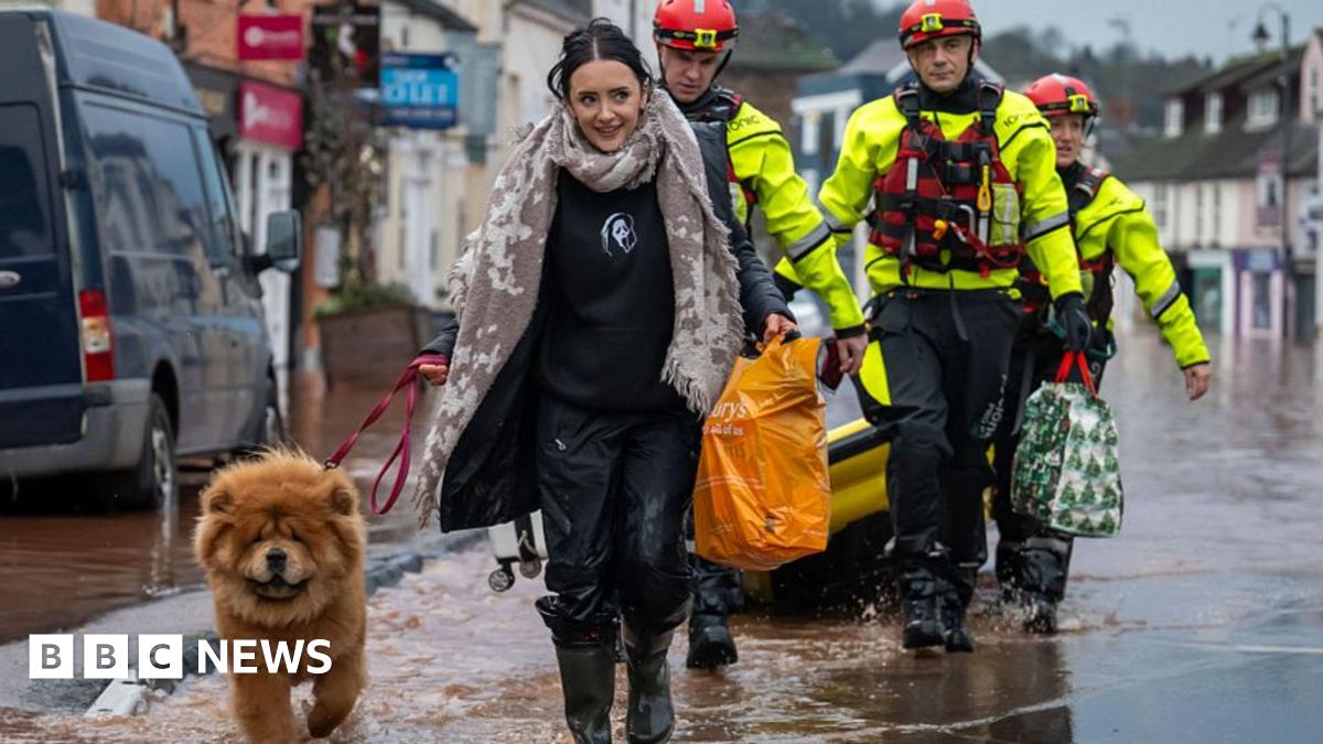 A composite image. On the left there are four rescuers in hi-vis wade through flooded street as a man in a hi-vis jacket pushes a person in a canoe. There is a pub and a shop. They are both white buildings. On the right the same pub can be seen with the flood waters now resided, there is a white car in front with residue from the floods along with black and white warning tape.