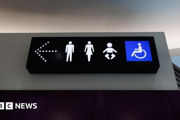 A photo shows a toilet sign with male, female, child and disabled icons