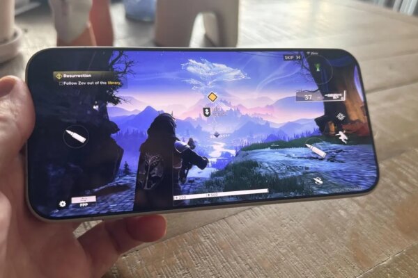 A hand holding a phone that's playing a third-person shooter game.
