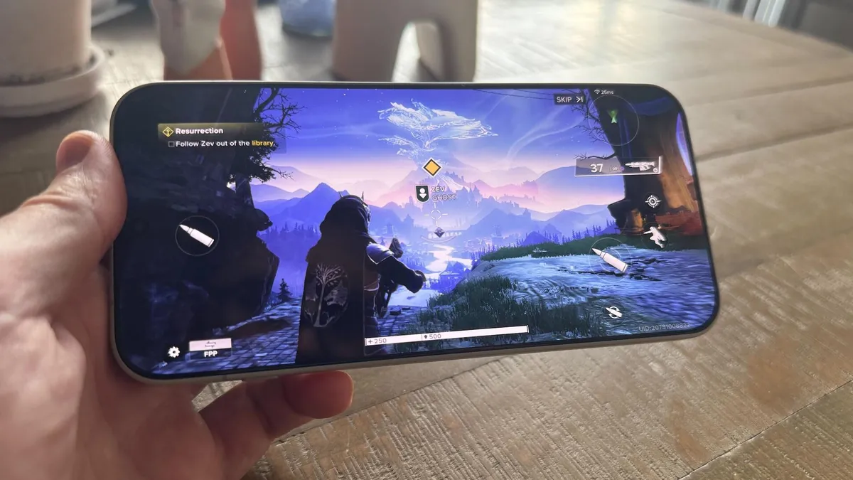 A hand holding a phone that's playing a third-person shooter game.