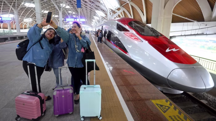 Passengers pose with a high-speed train at a station in Jakarta, Indonesia in 2025