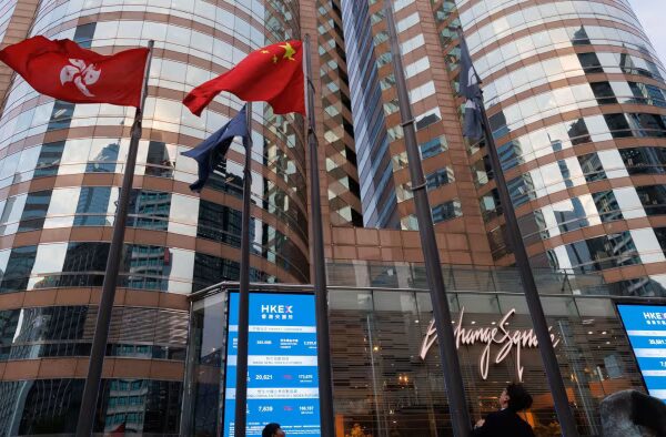 Hong Kong and China flags fly next to electronic boards displaying Hang Seng Index prices outside Exchange Square in Hong Kong.