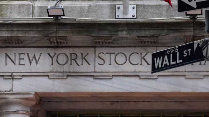 Alt text: The New York Stock Exchange entrance with a Wall Street sign in the foreground.