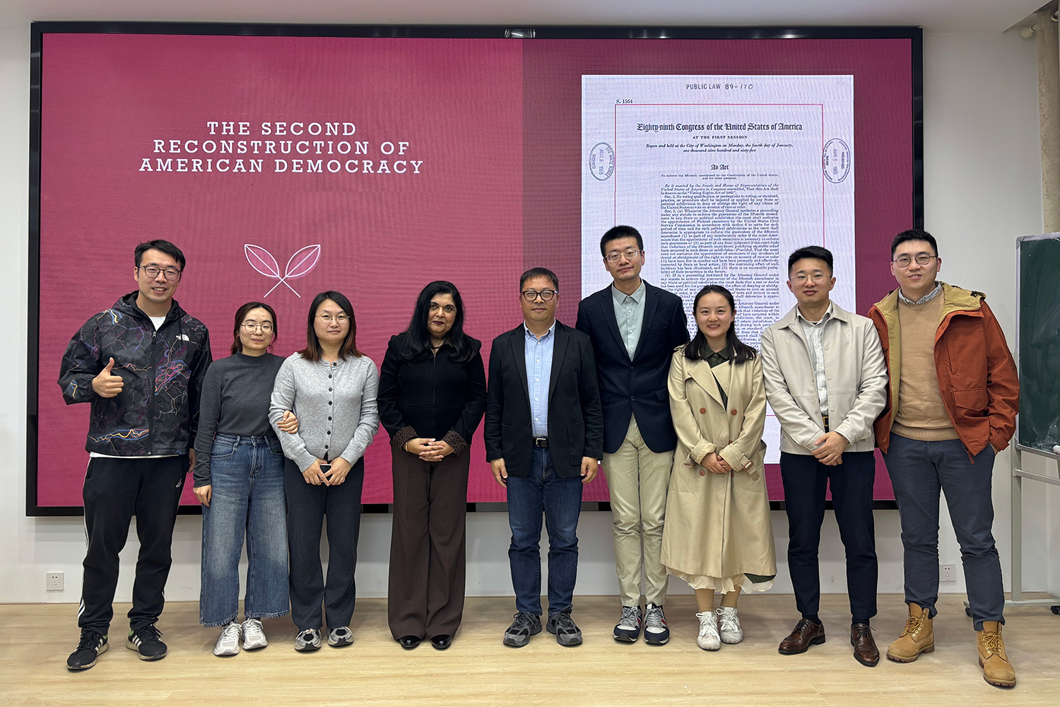 Nine people stand in front of presentation.