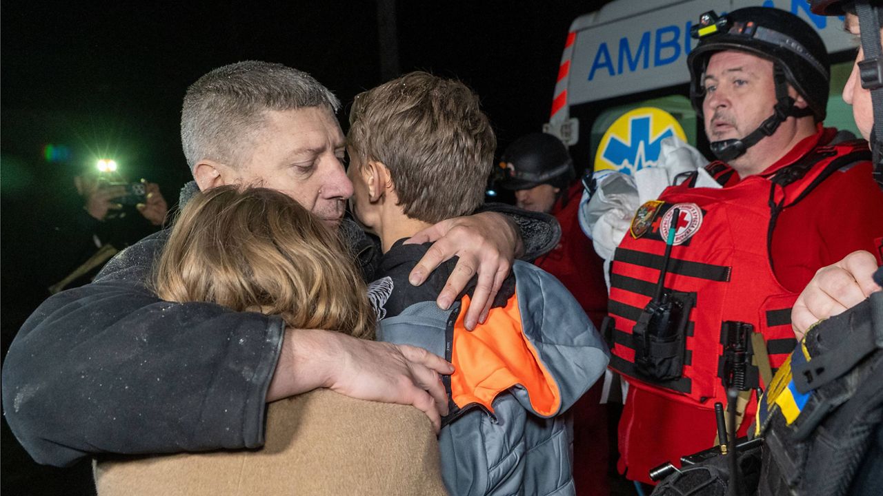 A man hugs his children as they react to the death of their mother killed by a Russian airstrike in Kharkiv, Ukraine, late Sunday, Nov. 23, 2025. (AP Photo/Andrii Marienko)