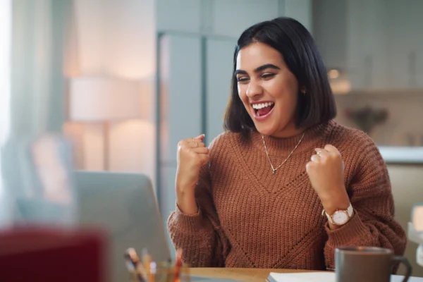 An investor cheers behind a laptop.